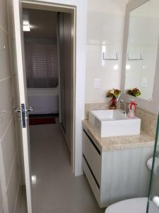 y baño con lavabo, espejo y bañera. en Apartamento 207, Edificio Kaluy, en Florianópolis