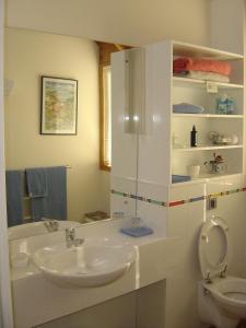 a white bathroom with two sinks and a toilet at Te Manaaki Villa in Russell