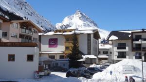 eine Gruppe von Gebäuden mit einem schneebedeckten Berg im Hintergrund in der Unterkunft Hotel Toni in Galtür