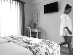 プラキアスにあるIRIDA Studios Hotel & Poolのテーブルとベッドのある部屋を歩き過ぎる女性