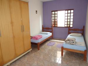 サン・ロケ・デ・ミナスにあるCasa Serra da Canastra - Chicóのベッド2台、キャビネット、窓が備わる客室です。