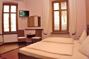 a bedroom with two beds and a table and two windows at Hotel-Restaurant Moselblümchen in Bernkastel-Kues