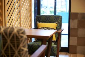 a chair with a yellow pillow sitting next to a table at DEL style Osaka Higashi Temma by Daiwa Roynet Hotel in Osaka