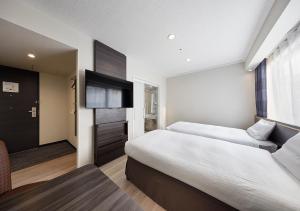 a hotel room with two beds and a flat screen tv at Via Inn Nagoya Station Tsubaki-cho in Nagoya