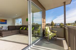 a balcony with glass doors and a couch at The Lookout in Mapua