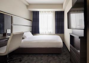 a hotel room with a bed and a desk and a chair at Via Inn Nagoya Station Tsubaki-cho in Nagoya