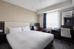 a hotel room with a large white bed and a desk at Via Inn Nagoya Station Tsubaki-cho in Nagoya