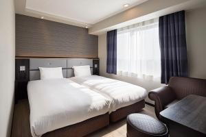 a bedroom with a bed and a desk and a chair at Via Inn Nagoya Station Tsubaki-cho in Nagoya