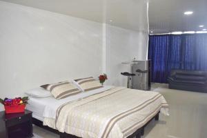 a bedroom with a large bed and a chair at Hotel Los Cristales in Pereira