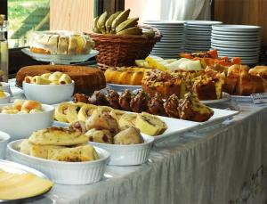 um buffet de diferentes tipos de alimentos em uma mesa em Pousada Aracema em Praia Grande
