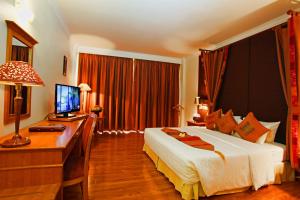 a bedroom with a bed and a desk with a computer at Angkor Century Resort & Spa in Siem Reap