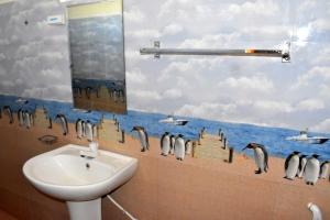 a bathroom with a sink and penguins on the wall at Green Heritage Holiday Resort in Mahiyangana +42 photos
