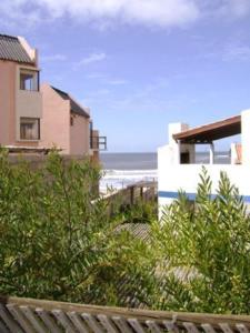 vistas a una playa con una casa y al océano en Cabañas Aguamarina en Punta Del Diablo