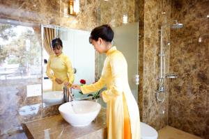 a woman standing in front of a sink in a bathroom at NỮ HOÀNG HOTEL in Phan Rang