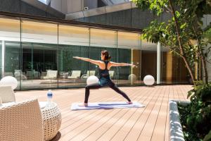 a woman doing a yoga pose on a yoga mat in a courtyard at Cerulean Tower Tokyu Hotel, A Pan Pacific Partner Hotel in Tokyo