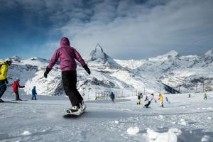a person riding a snowboard down a snow covered mountain at Hotel Butterfly, BW Signature Collection in Zermatt