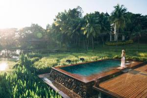 湄林的住宿－Four Seasons Resort Chiang Mai，站在花园游泳池旁的女人