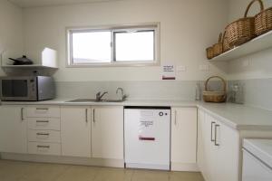 Una cocina con gabinetes blancos y un fregadero y una ventana. en Cooper's Country Lodge, en Eromanga 5 fotos más