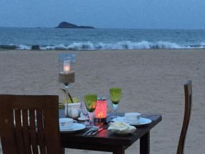 a table on the beach with a meal and wine glasses at Nilaveli Beach Resort - Level 1 Certified in Nilaveli