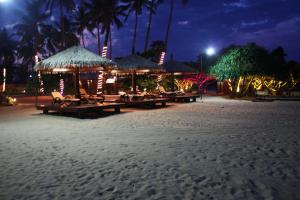 a beach with tables and umbrellas at night at Nilaveli Beach Resort - Level 1 Certified in Nilaveli