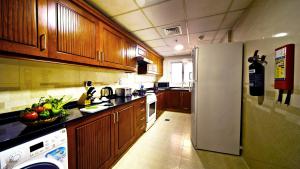 a kitchen with wooden cabinets and a refrigerator at Rose Garden Hotel Apartments - Bur Dubai in Dubai +63 photos