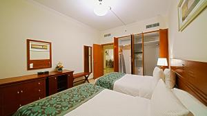 a hotel room with two beds and a dresser at Rose Garden Hotel Apartments - Bur Dubai in Dubai