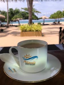 a cup of coffee sitting on a table near the beach at Nilaveli Beach Resort - Level 1 Certified in Nilaveli