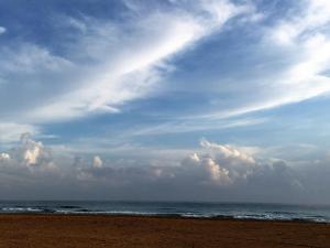 a beach with a cloudy sky and the ocean at Nilaveli Beach Resort - Level 1 Certified in Nilaveli