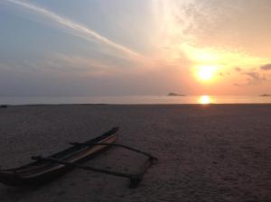 a boat on the beach with the sunset in the background at Nilaveli Beach Resort - Level 1 Certified in Nilaveli