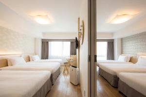 a hotel room with three beds with white sheets at Karaksa Hotel Osaka Namba in Osaka