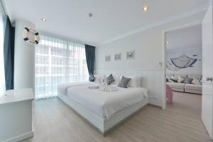 My Resort at Hua Hin by Charma في هوا هين: غرفة نوم بيضاء مع سرير كبير وأريكة