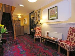 a room with two chairs and a table and a staircase at 19th Green Guesthouse in Killarney