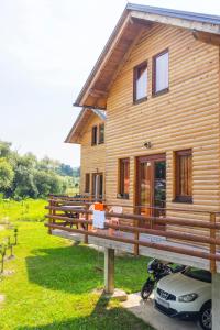 a wooden house with a car parked in front of it at Holiday homes Piralo in Kostajnica