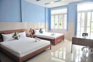 a bedroom with two beds and a desk and a sink at Hue Lovely Homestay in Hue