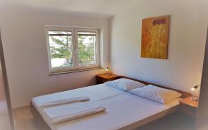 1 dormitorio con cama blanca y ventana en Apartments Vrtlici, en Stara Novalja