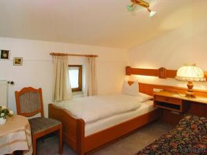 een slaapkamer met een bed en een bureau met een lamp bij Landhaus Freiblick in Bodenmais