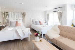 a white bedroom with two beds and a couch at Bijou Suites Granpia in Osaka