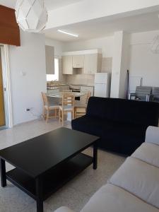 a living room with a black couch and a table at Flora Aparts in Dherinia