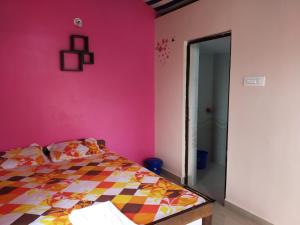 a bedroom with a pink wall and a bed at Prafulla Homestay in Kārwār