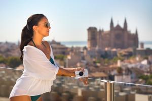 a woman in a white dress holding a camera on top of a city at Hotel Saratoga in Palma de Mallorca