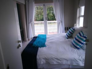 a bedroom with a white bed with blue pillows and a window at Island Nest in Knysna +6 photos