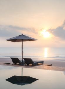 two chairs and an umbrella on a beach at Saai Resort in Bang Saphan Noi