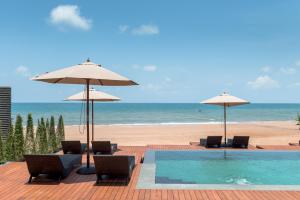 a pool with chairs and umbrellas next to a beach at Saai Resort in Bang Saphan Noi