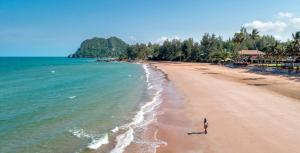 a person walking on a beach near the ocean at Saai Resort in Bang Saphan Noi