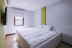 1 dormitorio con 1 cama blanca grande y ventana en Mei Ti Fashion Hotel, en Zhongli
