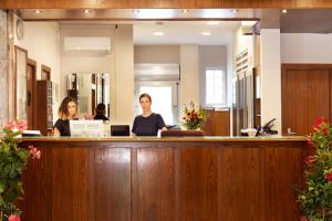 two women sitting at the reception desk of a law office at Hotel Corolle in Florence