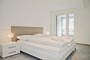 ein weißes Schlafzimmer mit einem weißen Bett und einem Fenster in der Unterkunft Apartment JungfrauCenter Bällenhöchst - GriwaRent AG in Interlaken