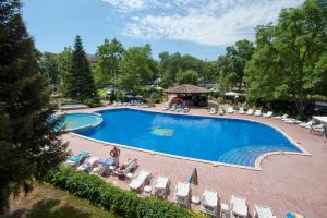 una piscina con sillas y gente sentada a su alrededor en Regina Hotel en Sunny Beach