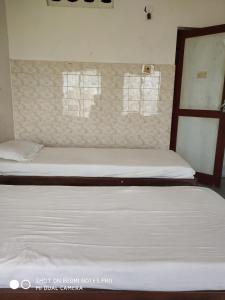 a bedroom with two beds and two windows at GP Mansion in Chennai