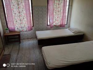 a small room with two beds and two windows at GP Mansion in Chennai